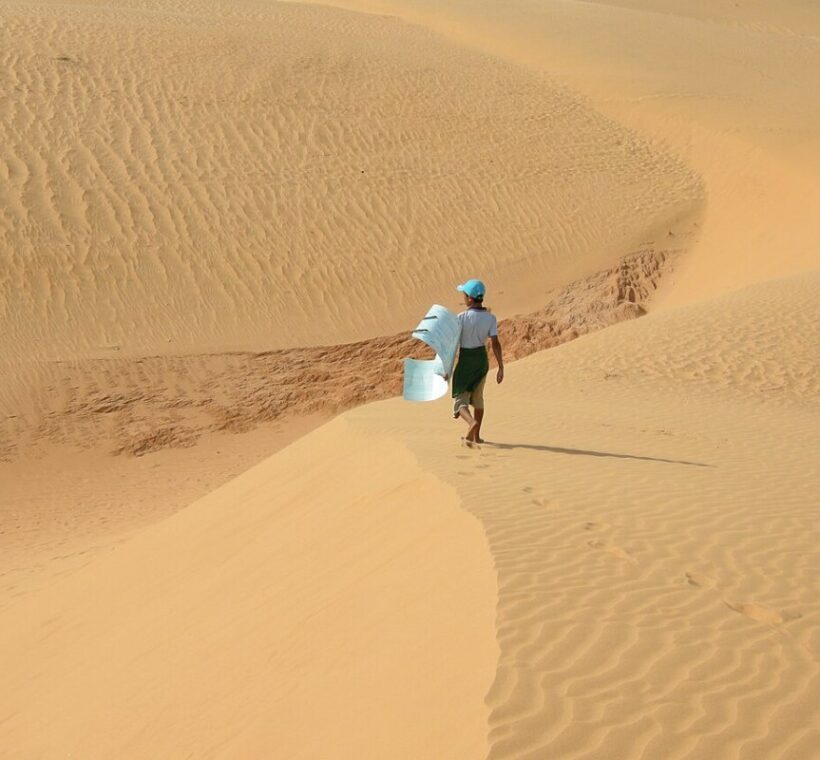 Walker crossing the golden sand dunes of Mui Ne in Vietnam