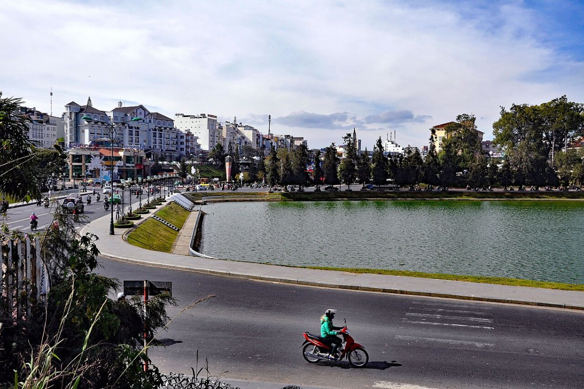 Road along the shore of Xuan Huong Lake with Da Lat town buildings